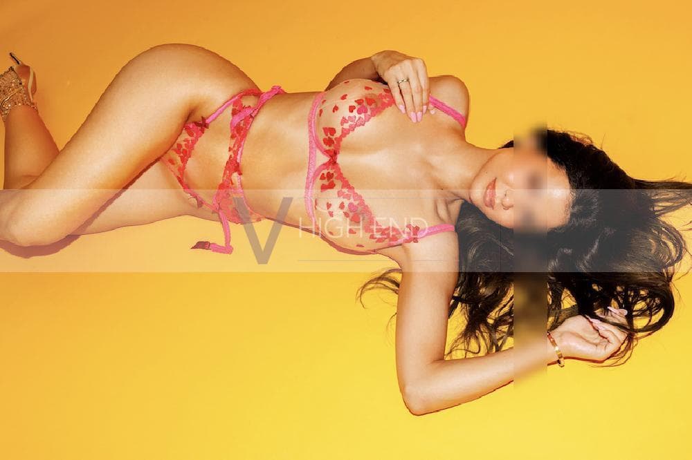 High class London escort Valerie is posing on a yellow plain background in a red matching lingerie underwear