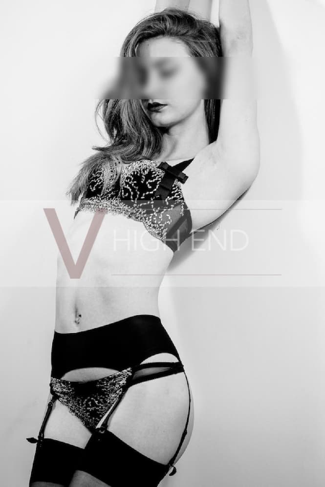 British escort in Poppy is posing in seductive black lingerie in a black-white photograph 