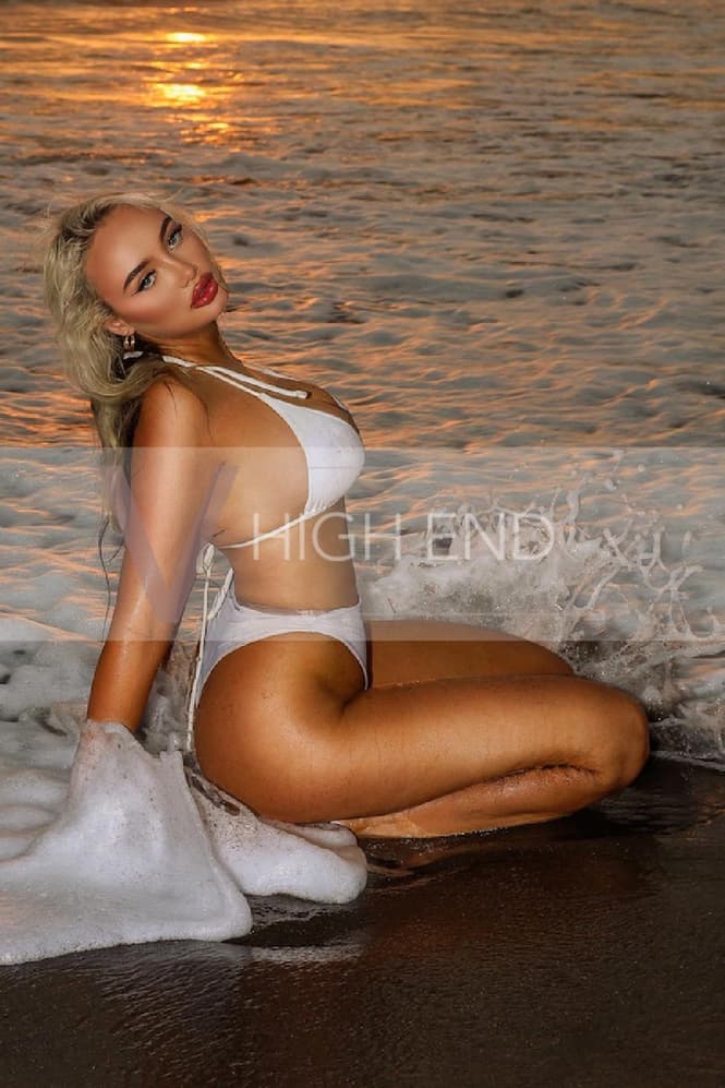 Sexy escort  Athena is posing in a water wearing white swimwear