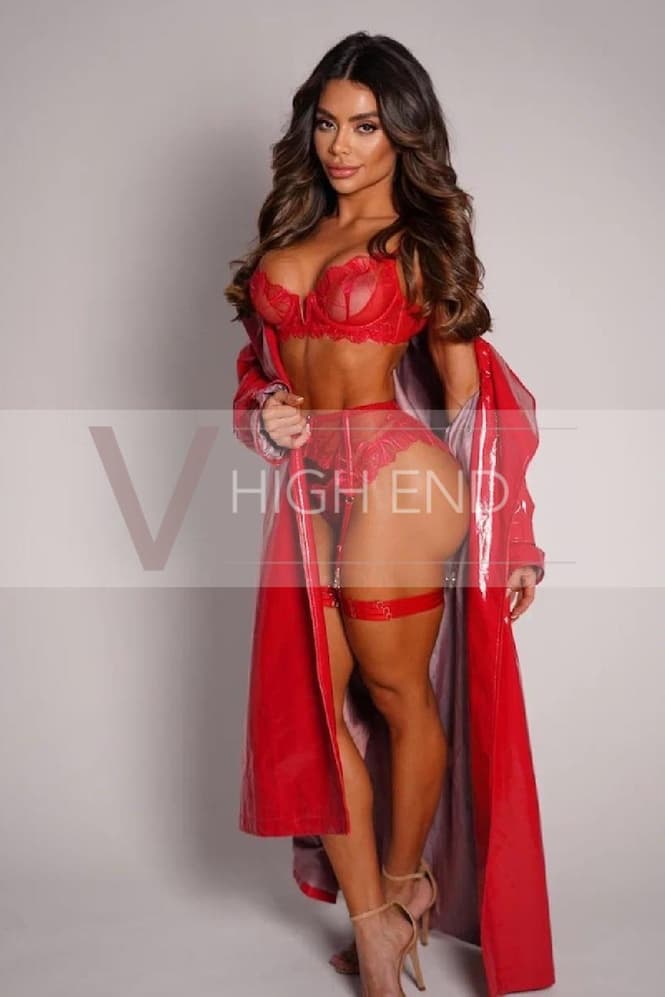 High-class escort Hailey is wearing red lingerie with a suspender belt and a red raincoat slipping down.